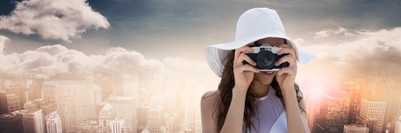 Digital composite of Close up of millennial woman with camera against skyline with cloudsの写真素材