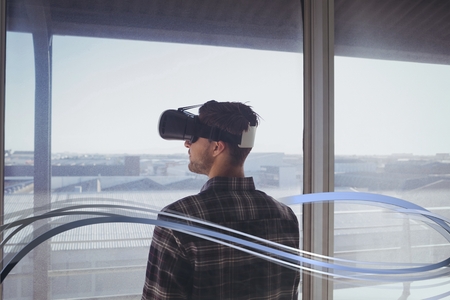 Digital composite of Man in VR headset standing behind interface