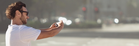 Digital composite of Man white shirt taking selfie against blurry street
