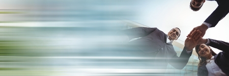 Digital composite of Low angle of business team putting hands together and blurry blue transitionの写真素材