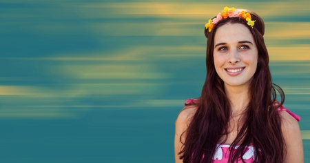 Digital composite of Millennnial woman with flowers in hair against blurry yellow and blue backgroundの写真素材