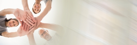 Digital composite of Low angle of volunteer team putting hands together and blurry white transitionの写真素材