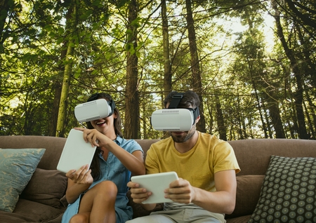 Digital composite of Couple in VR headsets playing against woods backgroundの写真素材