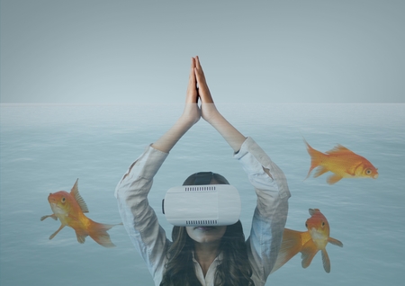 Digital composite of Woman in VR headset diving with fishes