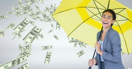 Digital composite of Happy business woman under umbrella with money rain against grey backgroundの写真素材