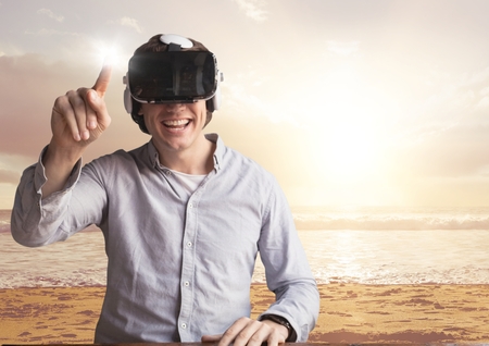 Digital composite of Happy man in VR headset touching flare against beach backgroundの写真素材