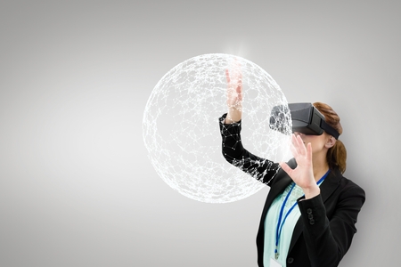 Digital composite of Woman in VR headset touching 3D sphere against white background