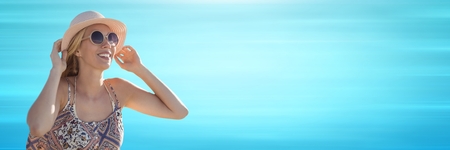 Digital composite of Woman in sunglasses and hat against blurry blue background