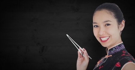 Digital composite of Close up of geisha with chopsticks against dark wood panelの写真素材