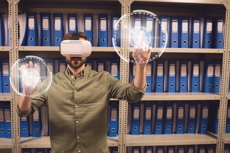 Digital composite of Man in VR headset touching interfaces with flares