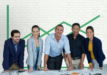 Digital composite of Happy business people at a desk standing against white wall with green graphic