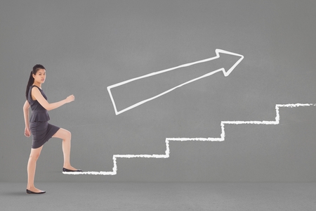 Digital composite of Business woman climbing stairs against grey background with white arrowの写真素材