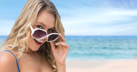 Digital composite of Woman at the beach holding sunglassesの写真素材
