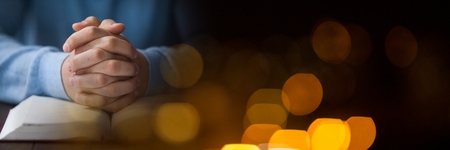 Digital composite of Hands on bible and black yellow bokeh transitionの写真素材