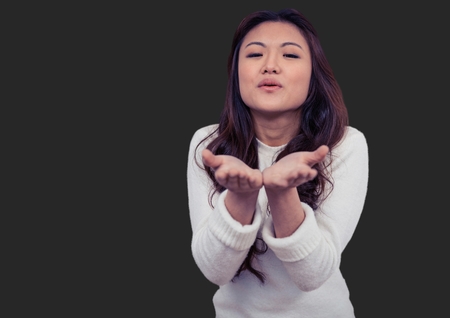Digital composite of Portrait of woman blowing kisses with grey background