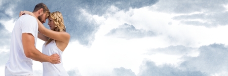 Digital composite of Couple embracing against cloudy skyの写真素材