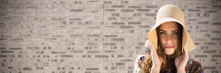 Digital composite of Portraiture of woman holding sun hat against brown brick wall