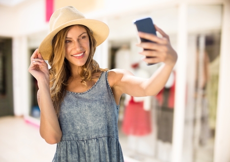 Digital composite of Woman taking casual selfie photo in front of shopping mallの写真素材