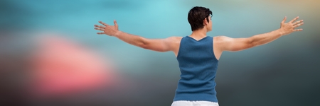 Digital composite of Back of man in training gear with arms out against blurry blue background