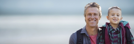 Digital composite of Father and son smiling against blurry beach