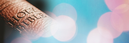 Digital composite of Close up of bible spine and blue pink bokeh transition