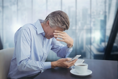Digital composite of Business man at a desk looking at a phoneの写真素材