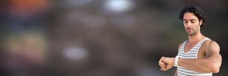 Digital composite of Man in training gear looking at watch against blurry brown backgroundの写真素材