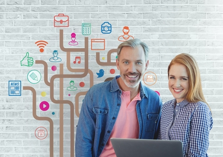 Digital composite of Happy business people holding a computer against white wall with graphics