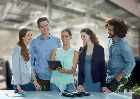 Digital composite of Happy business people at a desk looking at a tablet