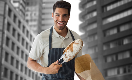 Baker packing loaf of bread against view of the city buildingsの写真素材