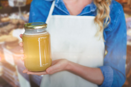 Midsection of woman holding jar against food products arranged in crateの写真素材