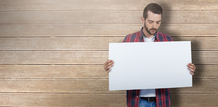 Male model holding placard against wooden surface with planksの写真素材