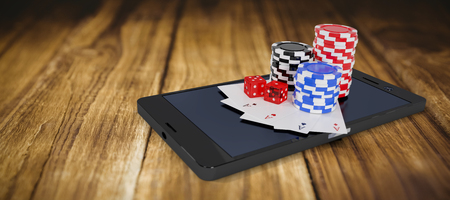 Stack of casino tokens with playing cards and dice on mobile phone against wooden tableの写真素材