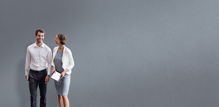 Business colleagues using digital tablet while walking  against grey background