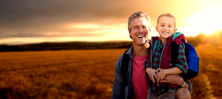Portrait of a crouching father beside son  against view of the countryside