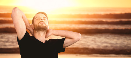 Young man with eyes closed against white background against image of a sunset over the wavesの写真素材