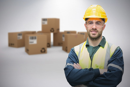 Manual worker wearing hardhat and eyewear against grey background