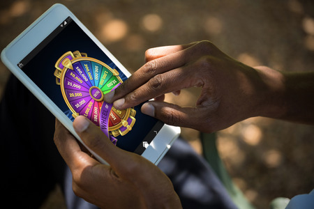Colorful wheel of fortune on mobile display against man using tablet computerの写真素材