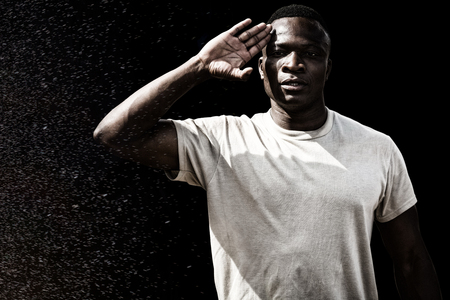 Black background against portrait of military soldier salutingの写真素材