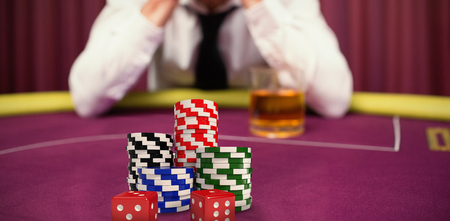 Dice with stack of colorful casino tokens against man betting his house at poker gameの写真素材