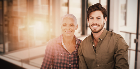 Portrait of a young man and a woman posing against businessman shaking hands with coworkerの写真素材