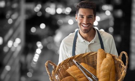 Baker holding bread in whisker basket  against glowing road in city at nightの写真素材