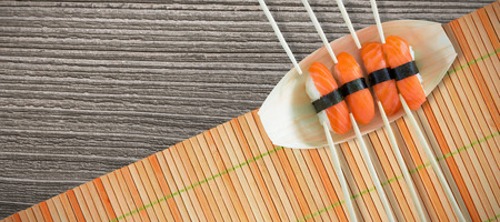 Close up of salmon sushi with chopsticks in plate against close up of sushi matの写真素材