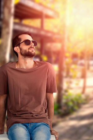 Full length of handsome model on seat against cropped image of park entranceの写真素材