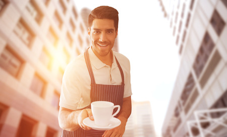 Waiter pointing a cup of coffee  against low angle view of office towersの写真素材