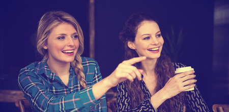 Smiling young woman showing something to friend at coffee shopの写真素材