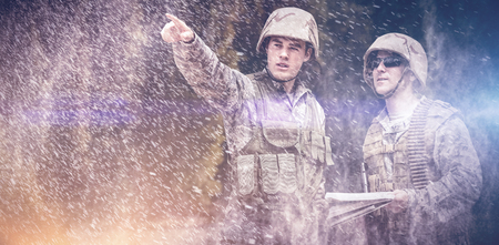Pine trees in forest  against military pointing away while soldier holding mapの写真素材