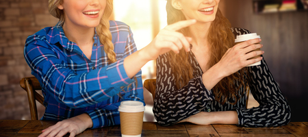 Women pointing forward in cafe  against empty chairs and tablesの写真素材