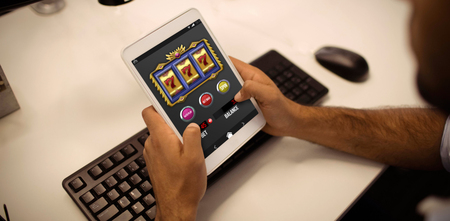 Casino slot machine app on mobile screen against businessman using digital tablet in officeの写真素材