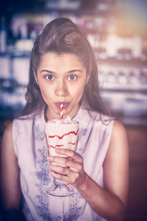 Portrait of young woman drinking smoothie at restaurantの写真素材